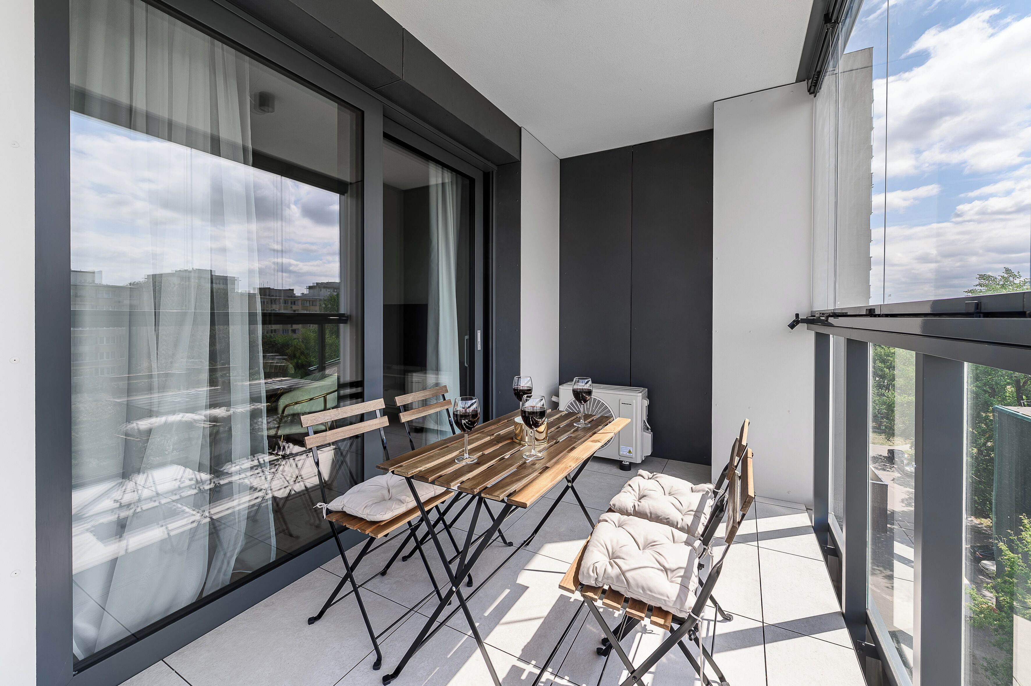 A balcony with a dining table, chairs, and a cushioned bench.