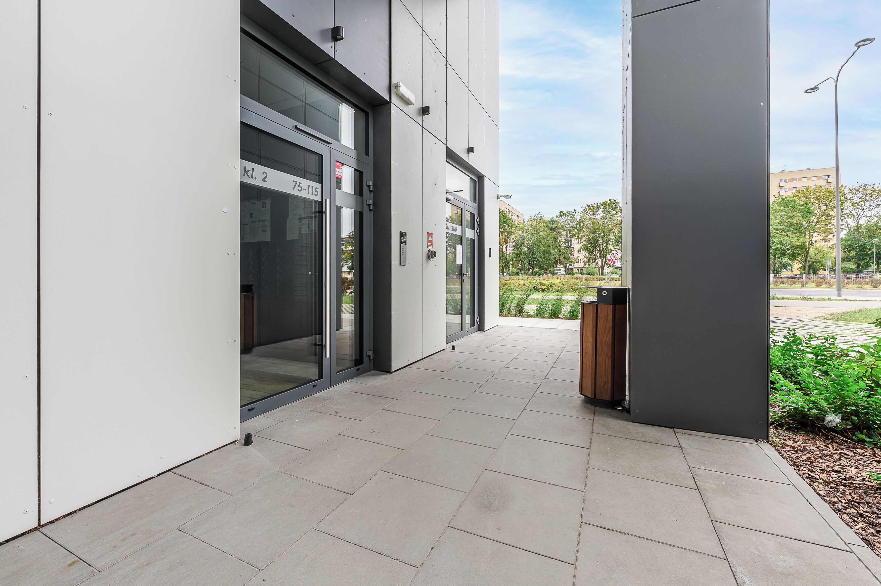 A modern building entrance with glass doors, a clear sky, and a paved pathway.