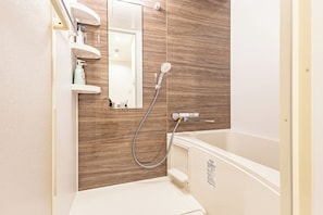 Ein Badezimmer mit einer Holzwand, einer Badewanne, einer Dusche und einem Spiegel.