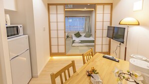 Ein kleines Hotelzimmer mit Küchenzeile, Essbereich, Bett mit Blick und Fernseher.
