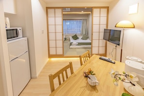 Ein kleines Hotelzimmer mit Küchenzeile, Essbereich, Bett mit Blick und Fernseher.