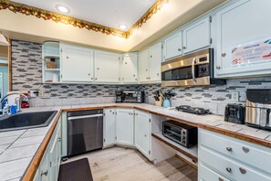 A modern kitchen with white cabinets, a stainless steel microwave, and a coffee maker. - Hungry Horse Hideout - Lower Level (Hungry Horse)