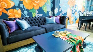 A modern living room with a sofa, coffee table, and a floral mural. - Maison Chinoise Midnight Muse: Chinatown & Songwat 4Bed 3Bath (Krung Thep Maha Nakhon)