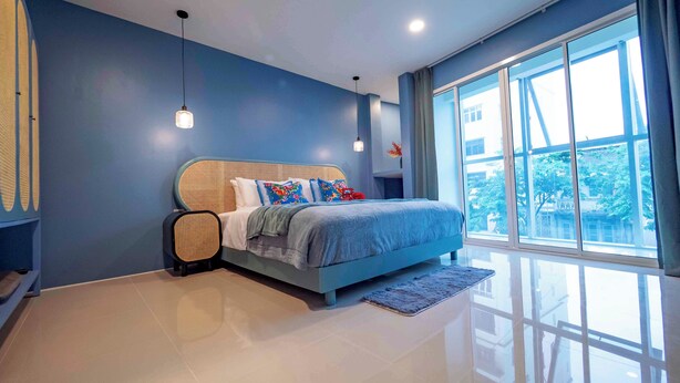 A modern bedroom with a large bed, a standing heater, and a view of the outside through large windows. - Maison Chinoise Midnight Muse: Chinatown & Songwat 4Bed 3Bath (Krung Thep Maha Nakhon)
