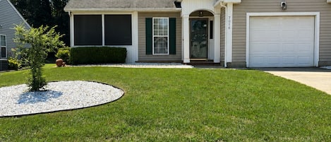 A two-story house with a garage, a covered front porch, and a well-maintained lawn.