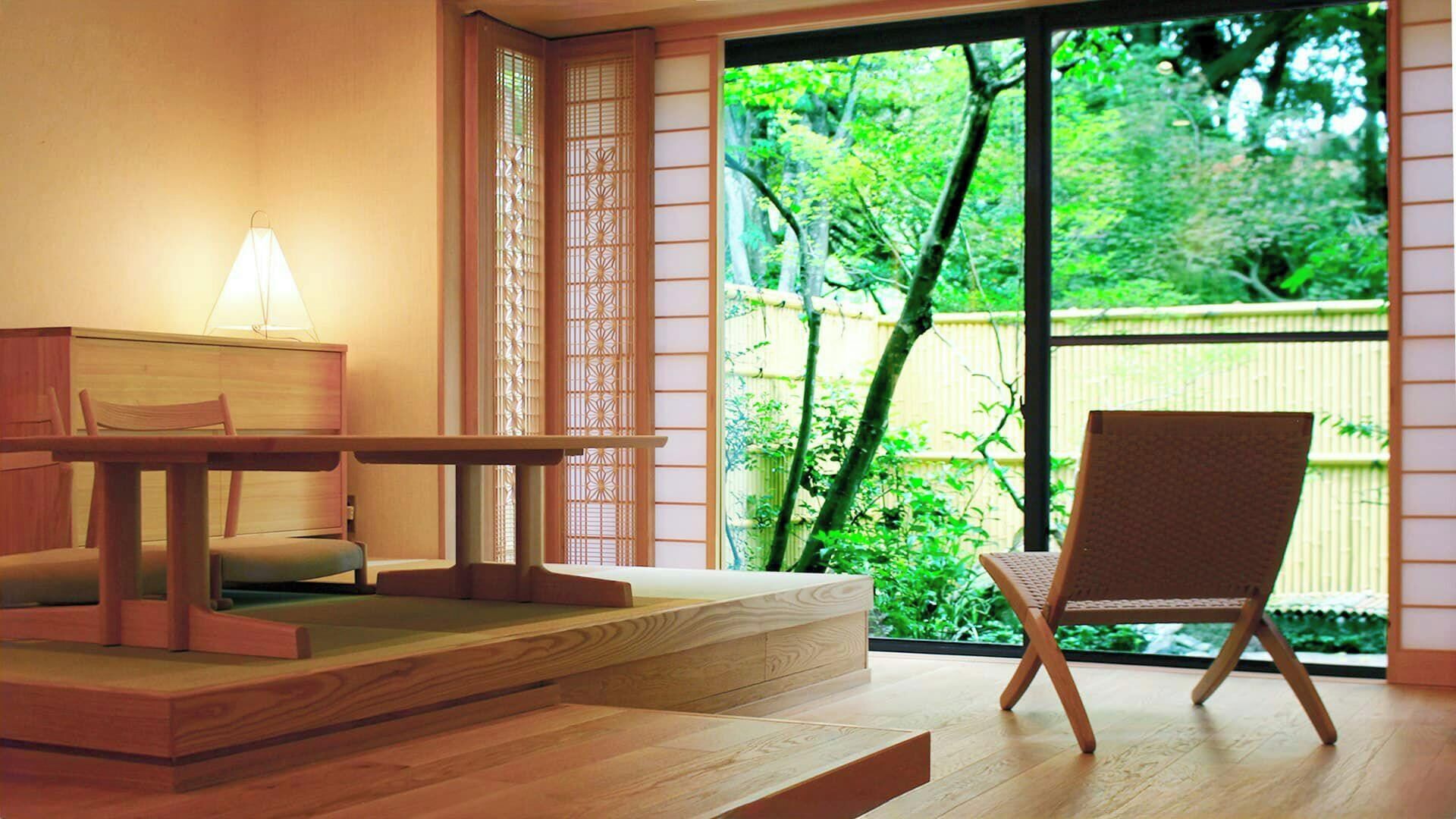 A room with a wooden desk, a chair, and a view of greenery through a sliding door.