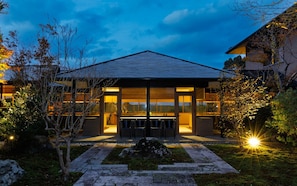 Una casa moderna con un amplio acceso de vidrio, asientos exteriores y un sendero de piedra.