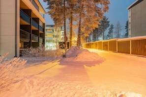 Lumipeitteinen polku johtaa modernia arkkitehtuuria edustavaan rakennukseen, jonka edessä on metalliaita.