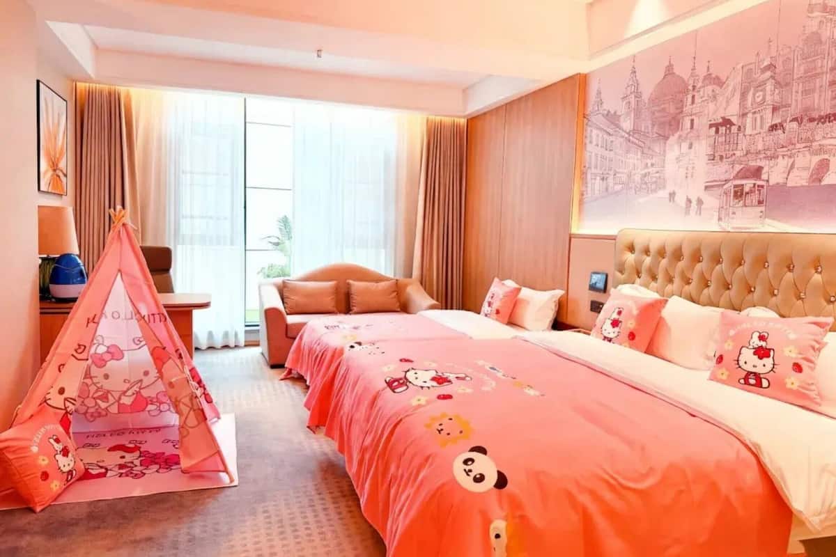 Una habitación de hotel con una cama grande, un sofá, una tienda temática de Hello Kitty y un mural con vista a la ciudad.