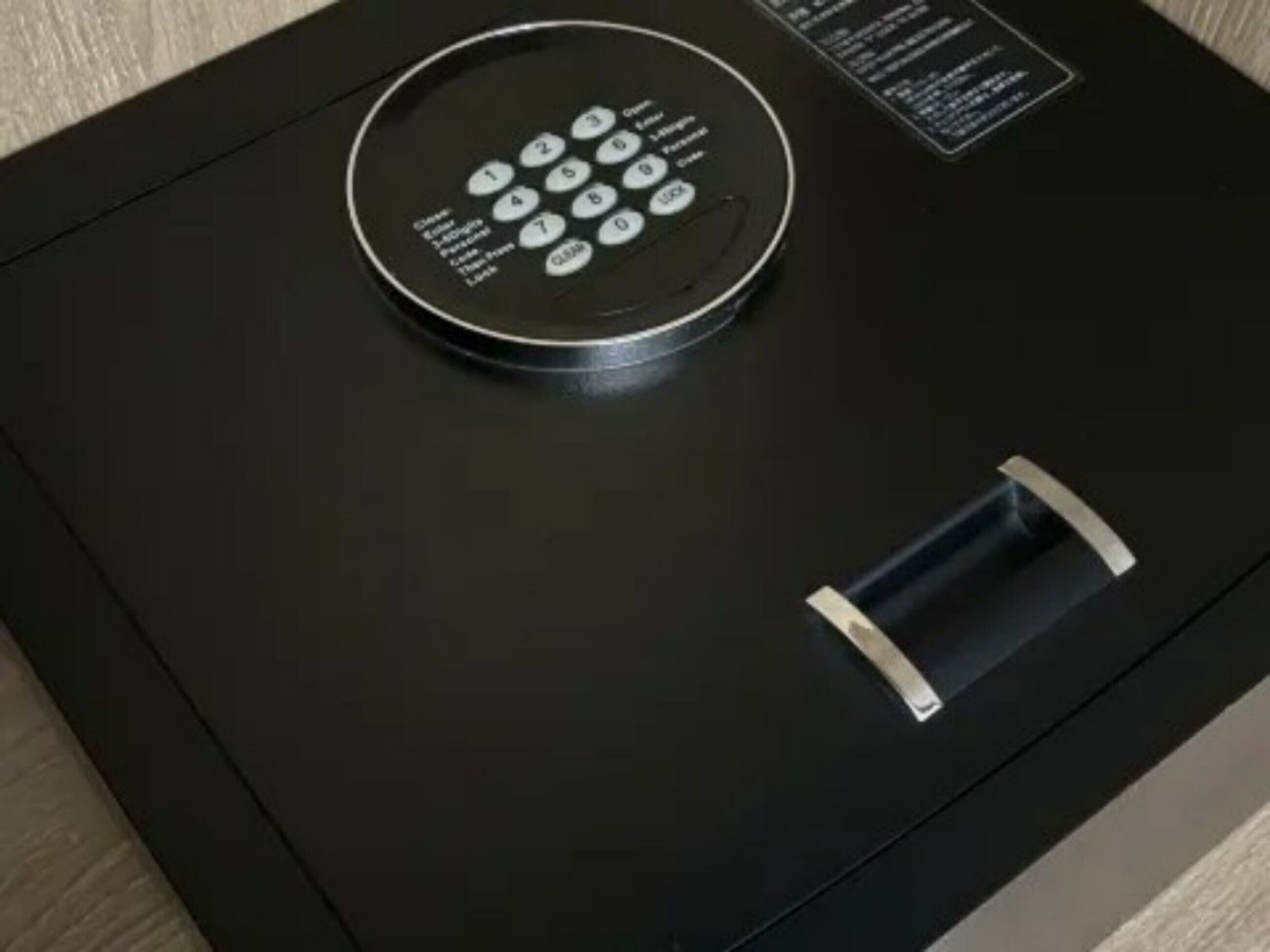 A black electronic keypad on a black surface, likely a lock or control panel.