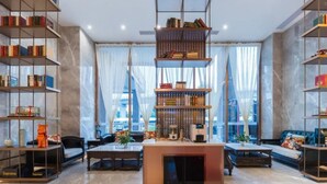 A modern living room with a marble floor, a central coffee table, a sofa, and two bookshelves filled with books. - Shengbaolong International Hotel (Wuhan)