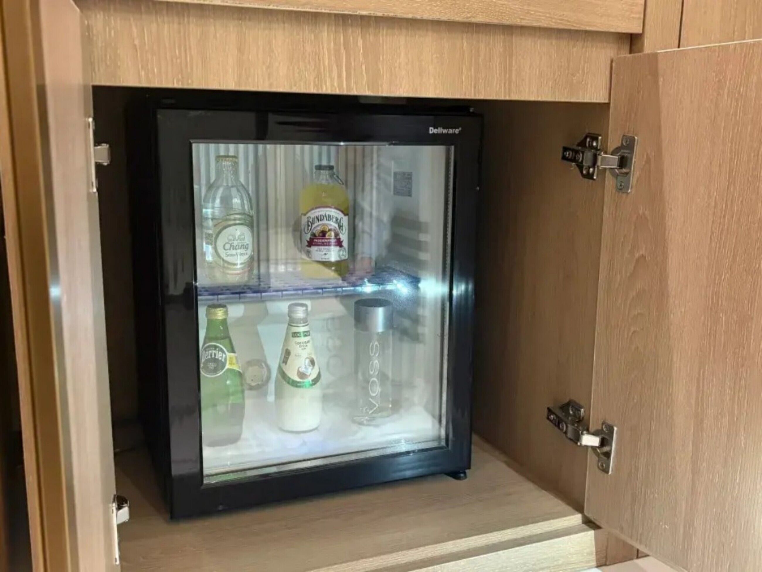 Mini-geladeira com porta transparente, contendo diversas bebidas.