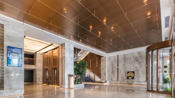 A spacious lobby with a polished marble floor, a staircase, and a large digital display. - Shengbaolong International Hotel (Wuhan)