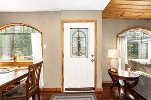 A room with a wooden door, a dining table with chairs, a sofa, and a lamp. - Hungry Horse Hideout - Upper Level with Hot tub (Hungry Horse)