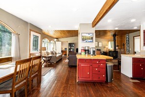A spacious kitchen with wooden flooring, a central island, and a dining area with a wooden table and chairs.