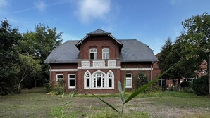 A large brick house with a symmetrical facade, multiple windows, and a central entrance. - Villa Jade - Earthgarden (Jade)