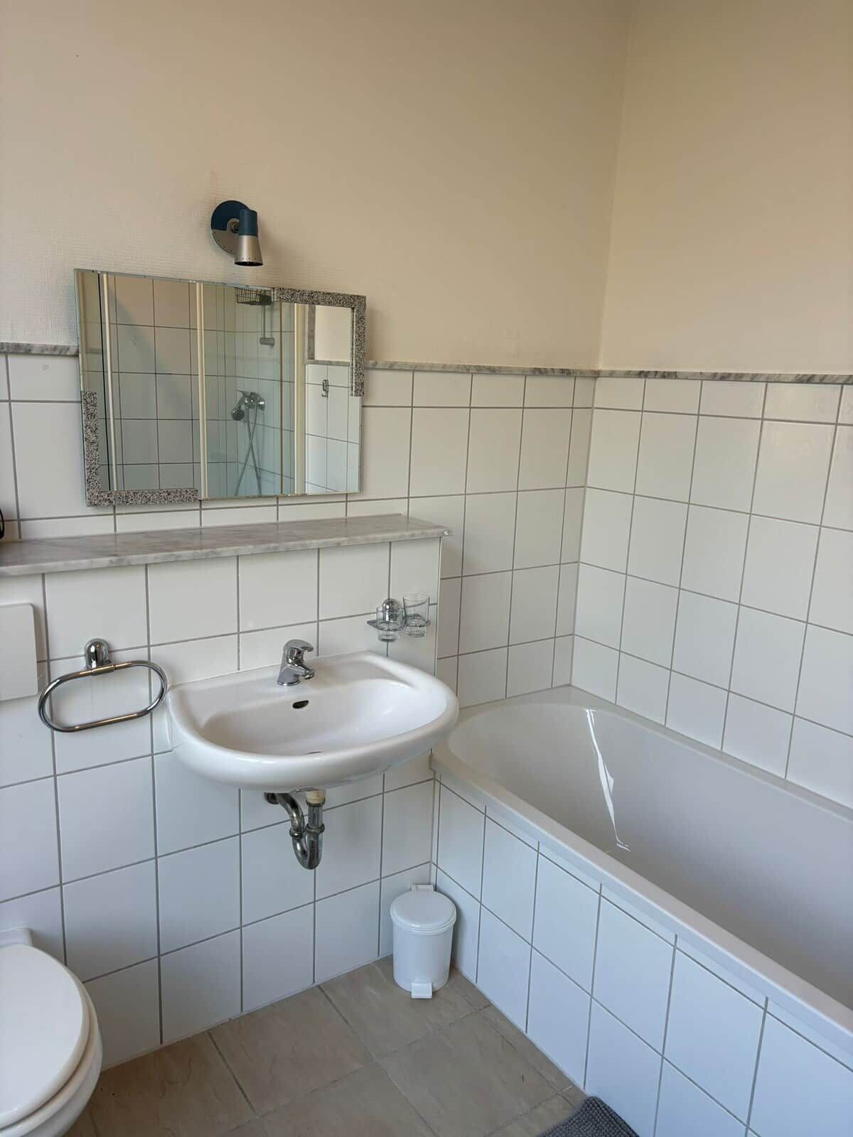 Un bagno con lavandino, specchio, water e vasca da bagno.