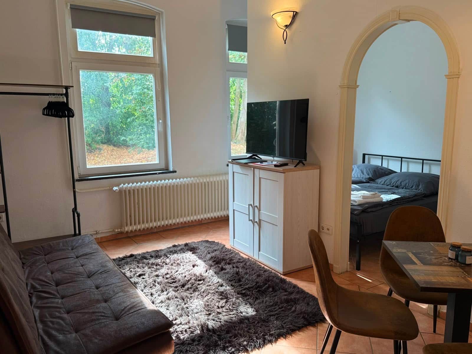 Een knus woongedeelte met een bank, een eettafel, een televisie en een bed.