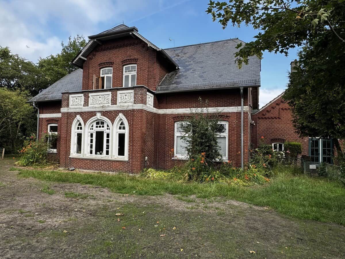 Een twee verdiepingen tellend bakstenen huis met een puntige dak en een voortuin.