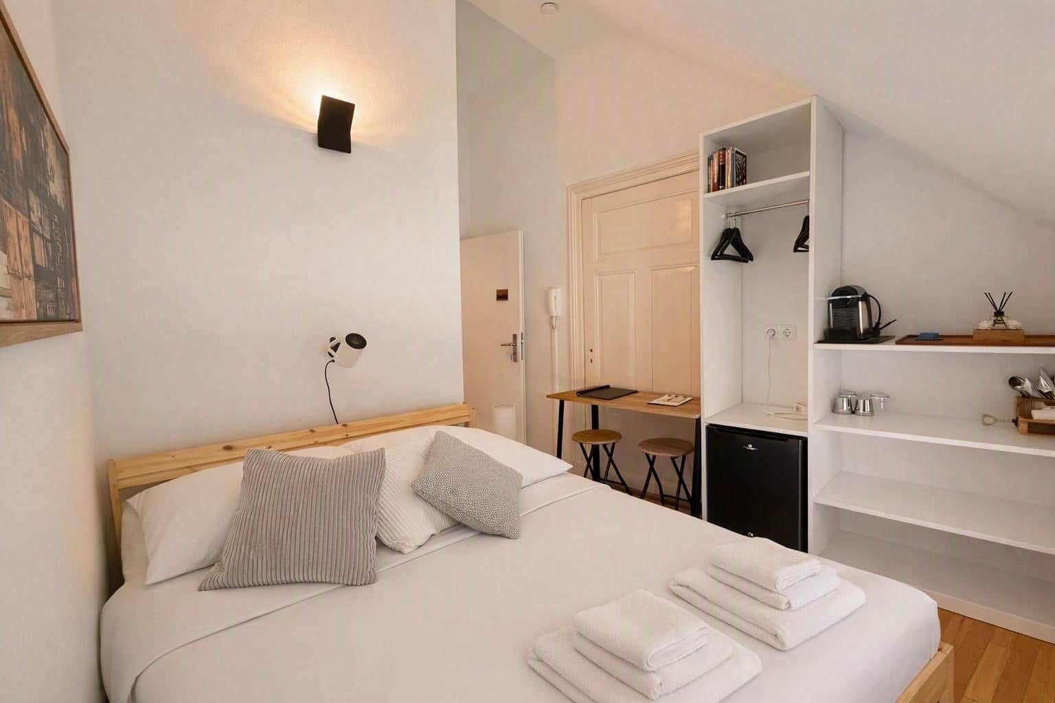 A neatly arranged bedroom with a bed, bedside lamp, and a small table with chairs.