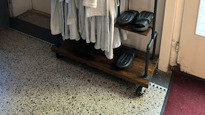 A rack with towels and slippers, a white door, and a small shelf with a tissue box.