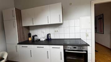 Eine Küche mit weißen Schränken, einer schwarzen Arbeitsplatte und einem eingebauten Backofen.