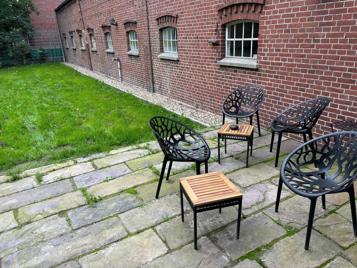 Un patio con suelo de piedra, mobiliario exterior y un edificio de ladrillo al fondo.