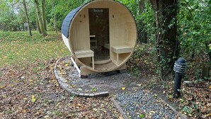 A wooden structure with a curved roof, a door, and a bench outside.