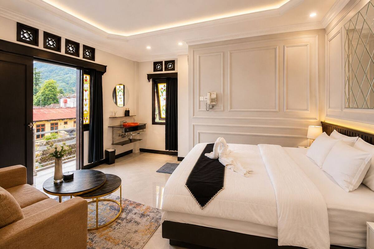 A hotel room with a bed, a desk, a chair, a bathroom, and a view of the outside.