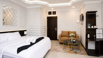 Habitación de hotel con cama, sofá, mesa de centro, televisión y minibar.