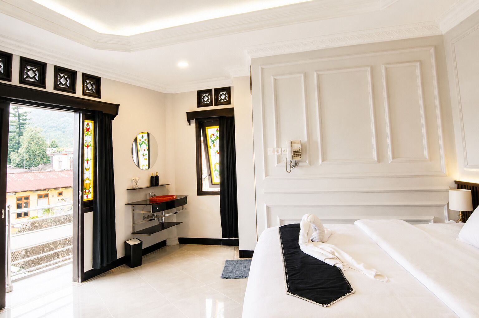 A hotel room with a bed, a bathroom with a sink, a mirror, and a telephone.
