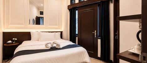 Une chambre d’hôtel avec un grand lit, une table de chevet, un bureau, un miroir et une armoire.