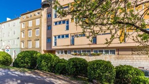 A multi-story building with a beige facade, a visible entrance, and a small garden area with trimmed bushes. - Apartment Antonella (Zadar)