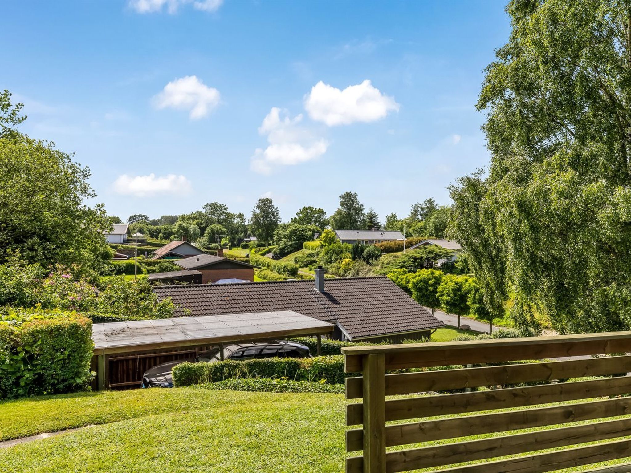 A residential area with houses, a wooden bench, and a clear sky.