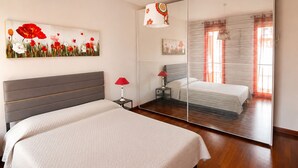 A bedroom with a bed, bedside table, lamp, and a large mirror. - Elegant apartment with a garage, two bedrooms, two bathrooms, and two terraces (Alba)