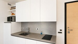 A modern kitchen with white cabinets, stainless steel appliances, and a black countertop. - Elegant apartment with a garage, two bedrooms, two bathrooms, and two terraces (Alba)