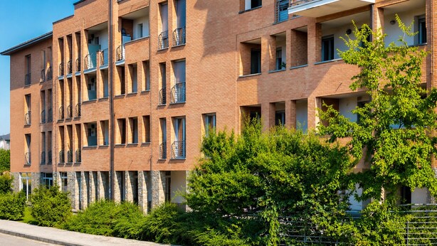 A multi-story residential building with balconies, brick facade, and surrounding greenery. - Elegant apartment with a garage, two bedrooms, two bathrooms, and two terraces (Alba)