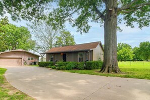 Ein eingeschossiges Haus mit Garage, Auffahrt und einem großen Baum davor.