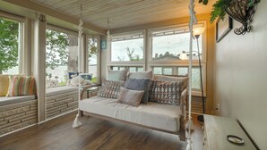 A cozy room with a hanging swing, large windows, and a view of the outdoors. - Game Room, Fishing Cabin & Dock on Grand Lake! (Grove)