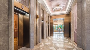 Un moderno vestíbulo de hotel con piso a cuadros, ascensores y una araña.