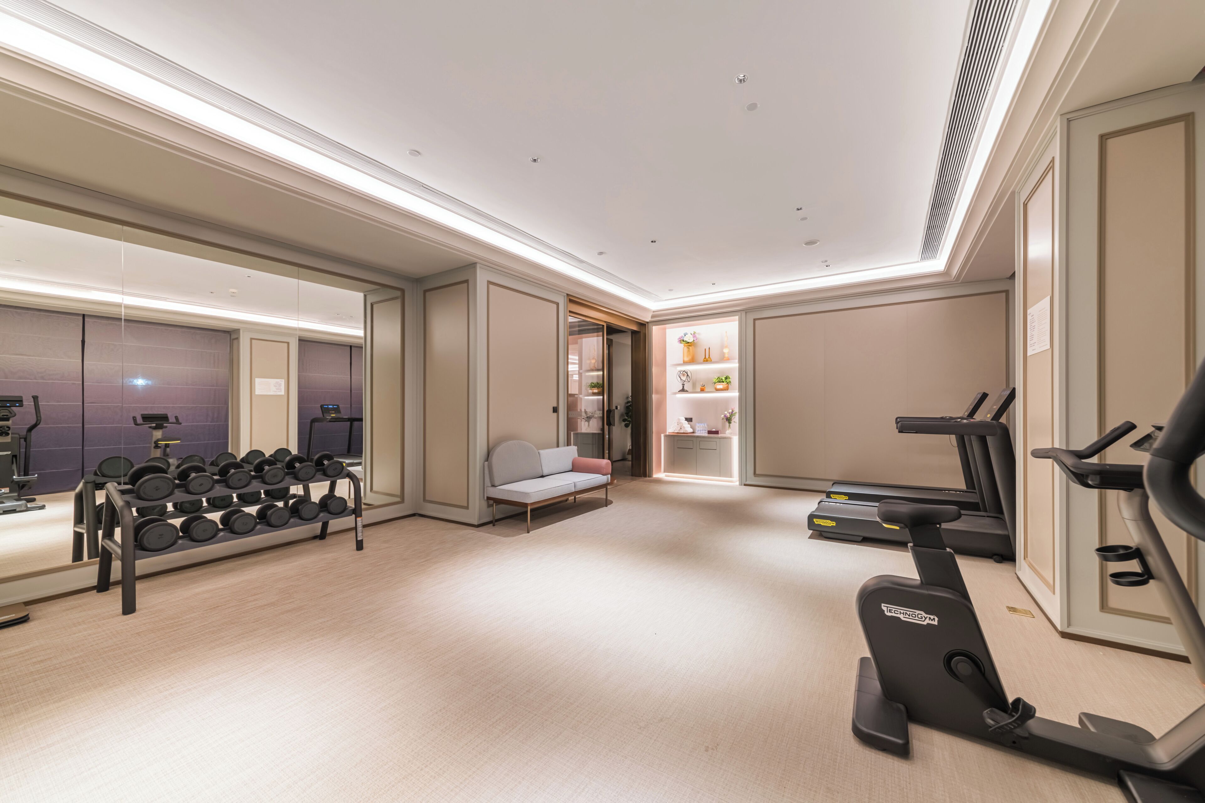 A gym with exercise equipment, a sofa, and a mirror.