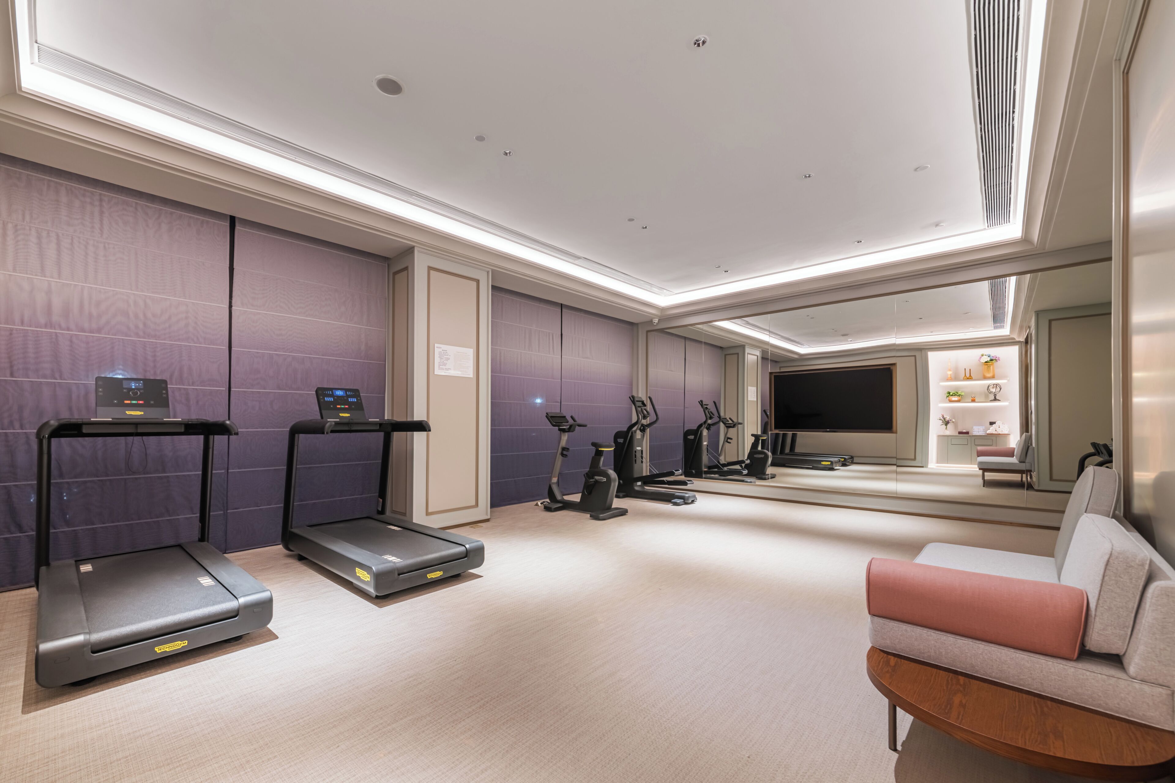A modern gym with treadmills, stationary bikes, and a mirrored wall.