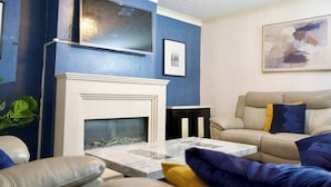A living room with a fireplace, a sofa, a coffee table, and a painting on the wall.