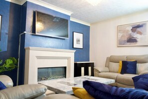 Una sala de estar con chimenea, un sofá, una mesa de centro y un cuadro en la pared.