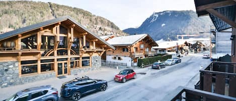 A wooden building with large windows, a balcony, and a mountain backdrop.