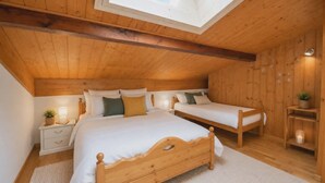Een slaapkamer met dakraam, twee bedden, een nachtkastje en een klein plankje.