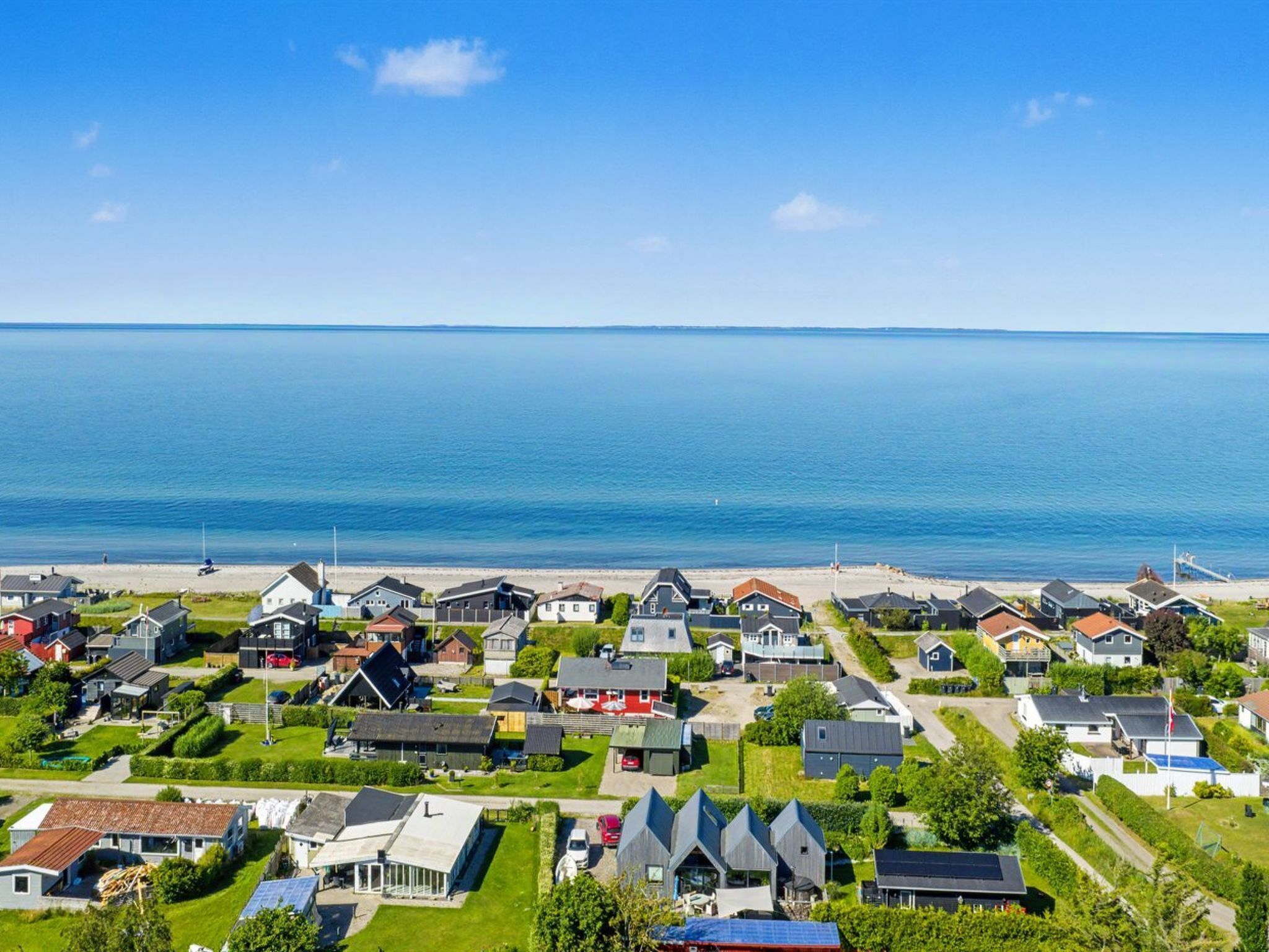 A coastal residential area with houses, a beach, and a clear view of the sea.