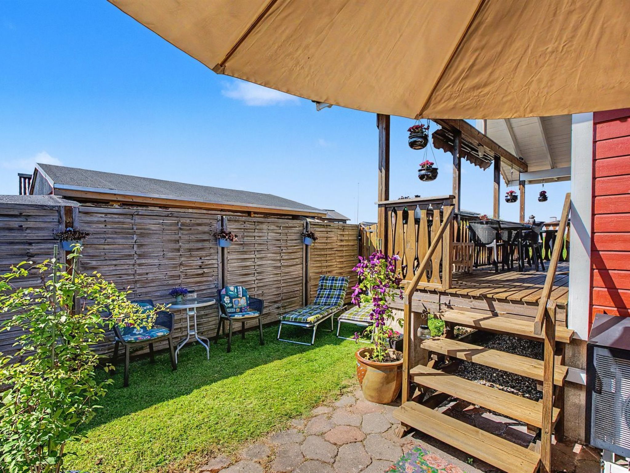 A patio with outdoor furniture, a wooden deck, and a covered area with a table and chairs.