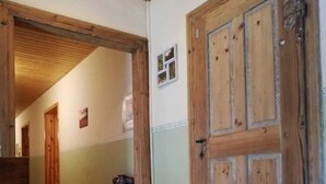 Um corredor com portas de madeira, uma pequena mesa com objetos e um banco.