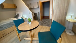 A compact room with a bed, a small table with chairs, a kitchenette, and a door leading to another room. - Apartment 'Zwei Betten Studio' with Wi-Fi (Lübeck)